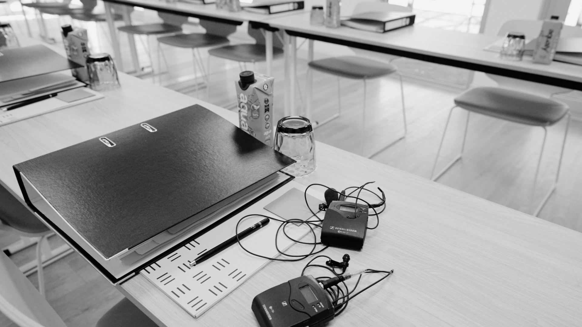 Salle de réunion du Club HERVEST préparée pour une session : rangées de tables avec classeurs, verres et microphones